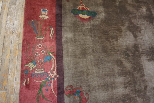 A red panel with a vase and floral pattern meets a wide, mottled grey field on wood flooring.