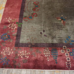 Distressed green and red floral rug with a dark border resting on weathered wood plank floors.