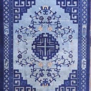 Blue rug with a pale field, dark blue geometric medallion, flowering vines, and detailed key pattern borders.