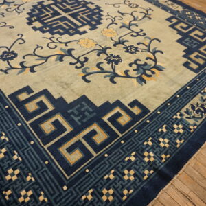 A sage green rug featuring scrolling floral designs and dark blue geometric borders on rustic wood floors.