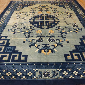 Slate blue rug featuring navy blue geometric designs, yellow floral accents, and wide plank hardwood flooring.