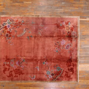 Low-pile rose rug featuring detailed multicolored birds and flowers rests on aged plank wood flooring.