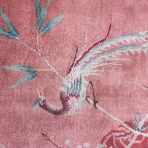 Rose rug detail showing a stylized bird and bamboo motif in pale blue, gray, and pink.