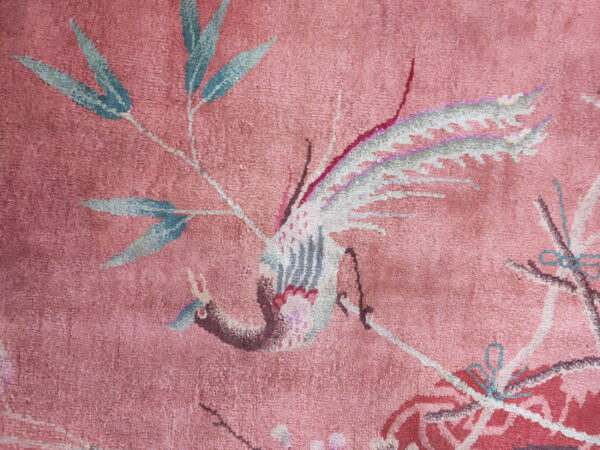 Rose rug detail showing a stylized bird and bamboo motif in pale blue, gray, and pink.