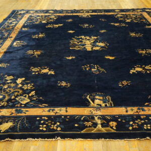 Deep blue high-pile rug featuring scattered gold and teal floral designs and a wide camel border on a wood floor.