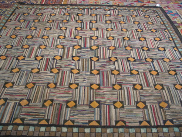 Geometric rug featuring alternating striped rectangles and orange diamonds, framed by a tiled border.