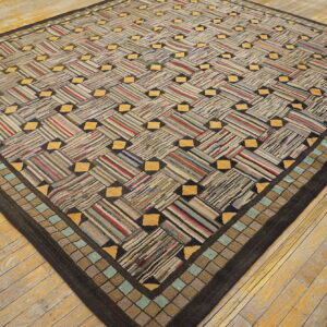 A dark-bordered rug with a striped gray, red, and yellow basketweave pattern rests on distressed hardwood floors.