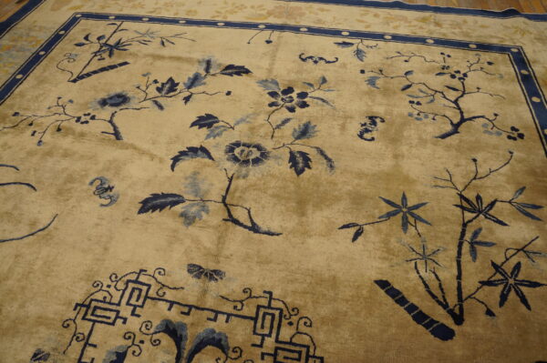 Beige rug featuring sprawling blue trees, flowers, and bamboo motifs with a detailed dark blue border.