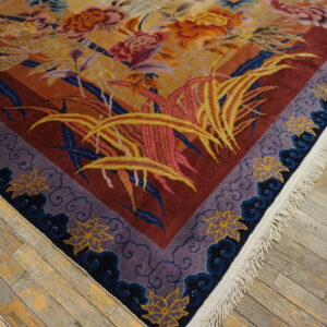 Multicolored rug featuring gold florals, red field, and purple cloud borders on distressed wood floor.
