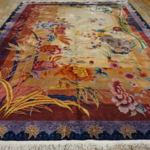 Vibrant multi-colored rug with floral and scenic patterns lies on distressed yellow wooden flooring.