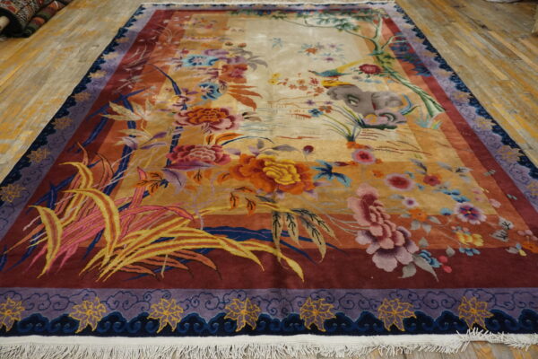 Vibrant multi-colored rug with floral and scenic patterns lies on distressed yellow wooden flooring.