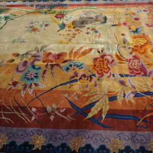 Plush rug with elaborate multi-colored floral and bird design on a gold-to-red striped ground.
