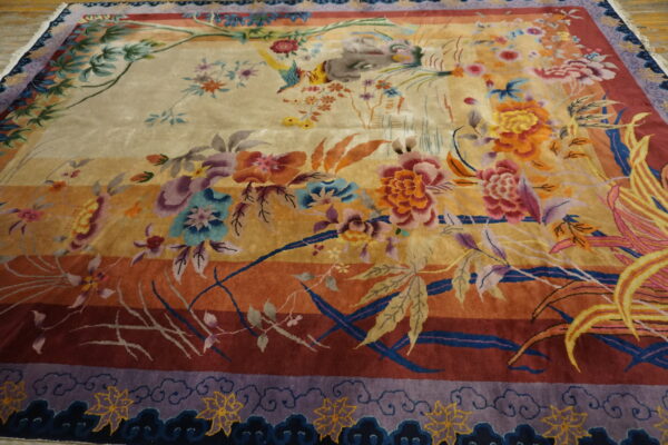 Plush rug with elaborate multi-colored floral and bird design on a gold-to-red striped ground.