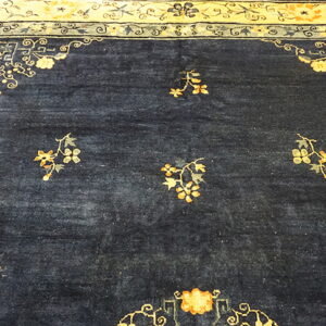 Deep indigo rug field with scattered gold florals and an ornate, wide cream and blue border.