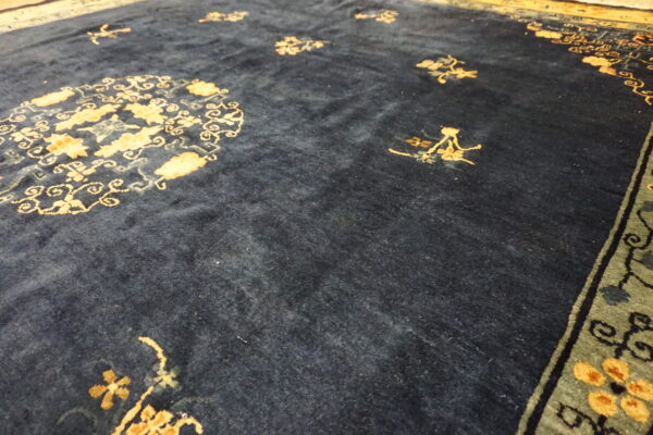 Plush dark blue rug with scattered gold floral motifs and a detailed green and gold border.