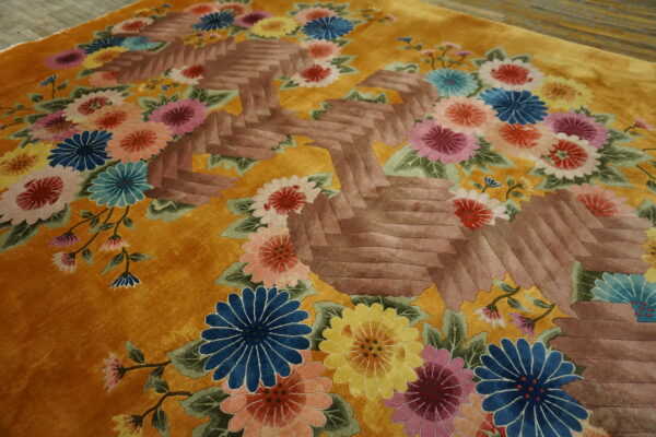 Gold rug with vibrant multicolor florals surrounding a sculpted brown geometric design.