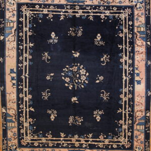 Navy blue rug with pale pink and beige borders, featuring intricate floral and architectural designs on a wood floor.