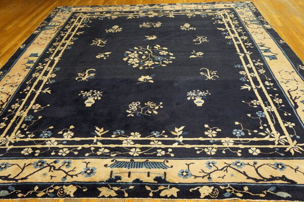 Navy area rug featuring beige and light blue floral motifs and pagoda details on a wood floor.