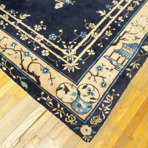 Dark blue and beige rug corner with intricate floral and pavilion patterns resting on wood planks.