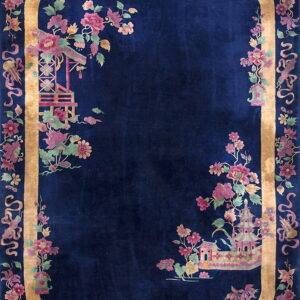 Rectangular dark blue rug with a gold border and pink florals surrounding Chinese-style architecture.
