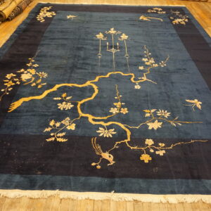 Large deep blue rug featuring a bold gold floral and bird pattern on wood planks.