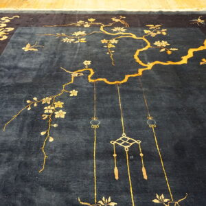 Deep blue rug with gold cherry blossom branches, birds, and decorative knot patterns on a wood floor.