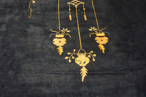 A dark blue, high-pile rug displays golden yellow stylized hanging lantern and vase patterns.