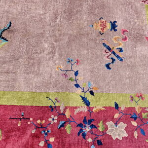 Mauve, magenta, and green rug featuring colorful scattered floral motifs and detailed borders.