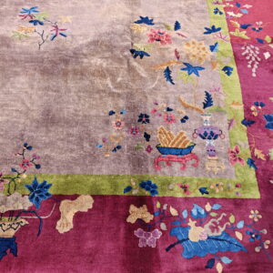 Floral rug with mauve center, green stripe, and magenta border shown on concrete pavement.