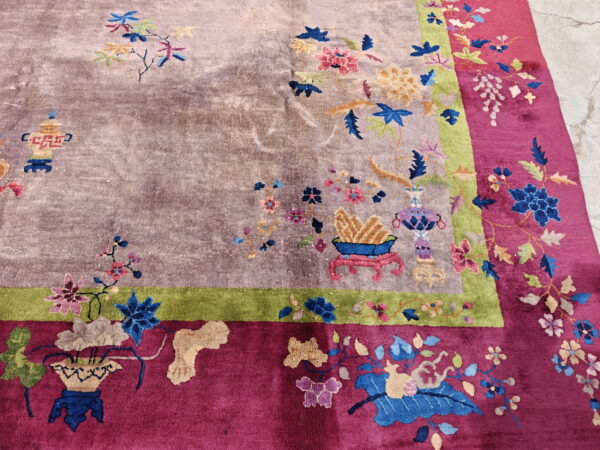 Floral rug with mauve center, green stripe, and magenta border shown on concrete pavement.