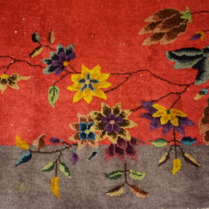 A brightly colored floral vine pattern separates the red rug field from the solid textured gray border.