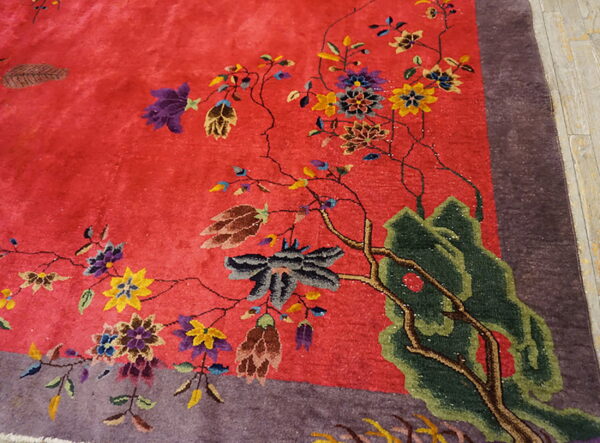 Vivid red rug featuring a detailed design of flowering branches and green scenery next to a purple border.