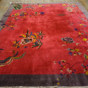 Fuchsia pink area rug featuring colorful floral vines and a wide purple border on wood plank flooring.