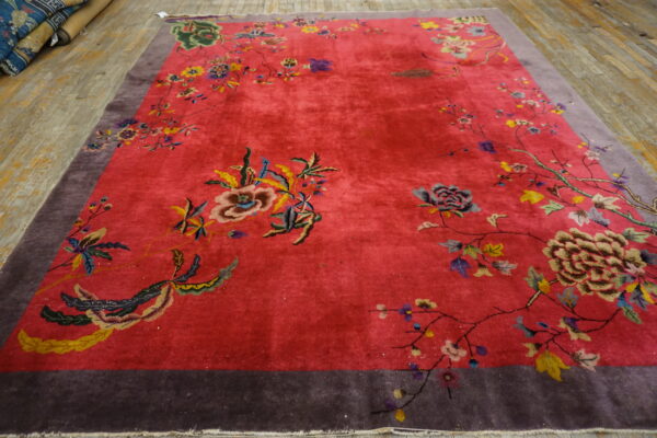 Fuchsia pink area rug featuring colorful floral vines and a wide purple border on wood plank flooring.
