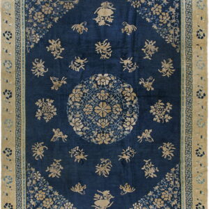 Navy blue rug with tan floral and animal figures, a central medallion, and a wide beige key-pattern border.