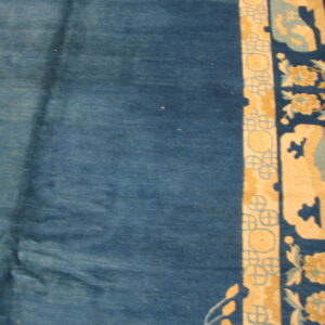 Deep blue rug field alongside a border featuring tan geometric patterns and stylized yellow and light blue florals.