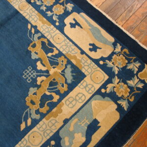 Deep blue rug corner with thick tan and pale blue stylized floral patterns visible on hardwood floor.