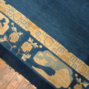 Stylized tan and light blue border details on a rich blue rug field resting on wood floors.
