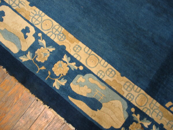 Stylized tan and light blue border details on a rich blue rug field resting on wood floors.