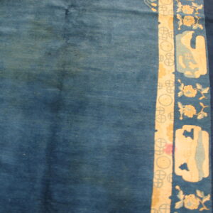 Mottled blue rug field beside a border featuring cream floral and abstract patterns on wood planks.