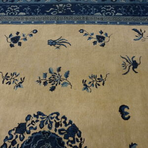 Beige rug with scattered blue floral motifs and a complex dark blue ornamental border.