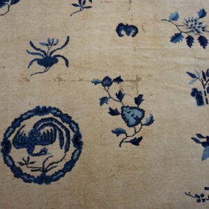 A light beige rug featuring spaced dark blue floral and circular bird patterns.