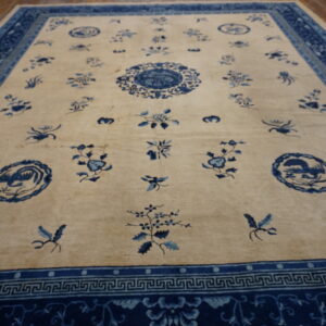 Cream and blue rug with scattered floral motifs and wide patterned borders visible on wooden flooring.