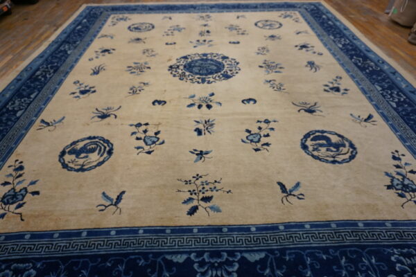 Cream and blue rug with scattered floral motifs and wide patterned borders visible on wooden flooring.