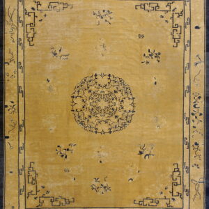 Mustard yellow rug with a navy blue medallion, scattered florals, and stepped geometric fretwork borders.
