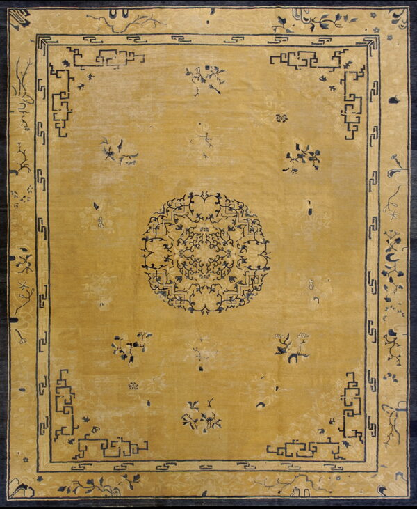 Mustard yellow rug with a navy blue medallion, scattered florals, and stepped geometric fretwork borders.