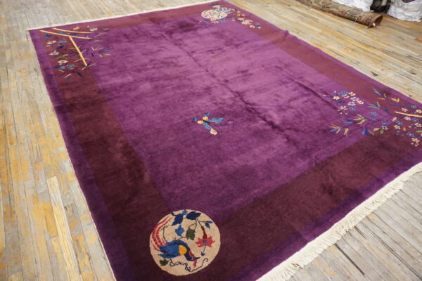 Deep purple high-pile rug with maroon border and colorful floral medallions on worn wooden flooring.