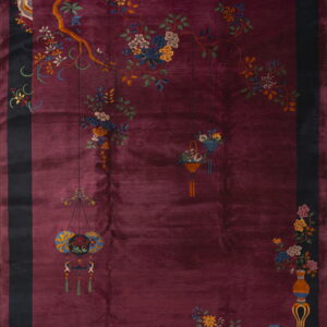 Deep burgundy rug with a dark border featuring multicolored flowering branches and decorative objects.