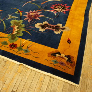Floral pattern rug with a blue field and bright yellow border on rustic light wood planks.