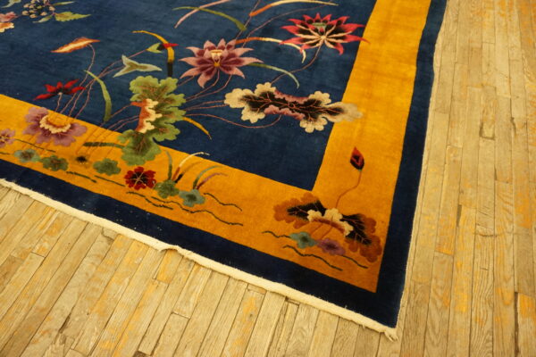 Floral pattern rug with a blue field and bright yellow border on rustic light wood planks.